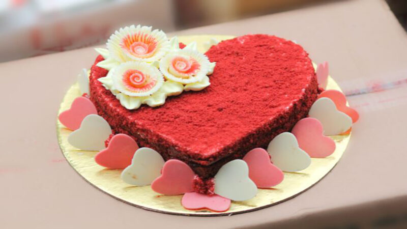 Bánh sinh nhật hình trái tim màu đỏ trang trí nhiều trái tim nhỏ xung quanh