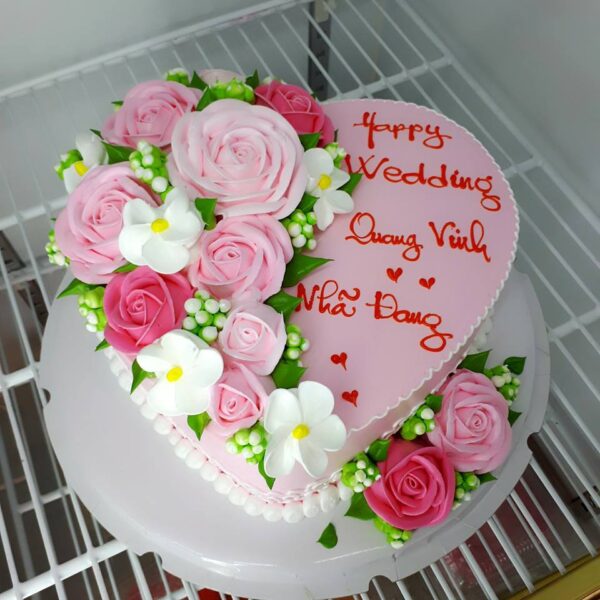 Bánh sinh nhật hình trái tim màu hồng trang trí những bông hoa