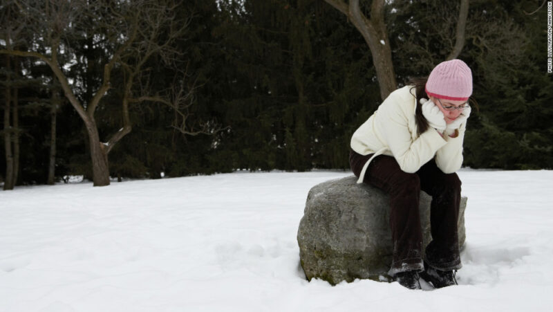 hình ảnh buồn một mình của cô gái ngồi trên tảng đá trong trời tuyết