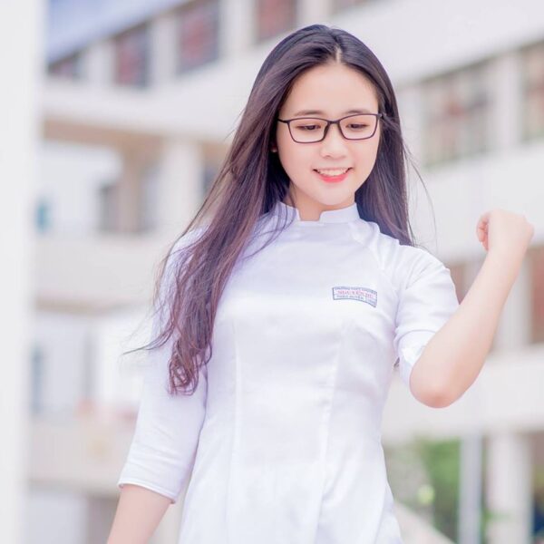 Das Bild eines schönen Mädchens mit langen Haaren, das eine sanfte 2K-Brille an der Seite eines langen Kleides trägt