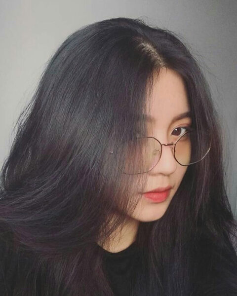 Bild eines schönen Mädchens mit langen Haaren und einer geheimnisvollen Brille, die ihr halbes Gesicht bedeckt