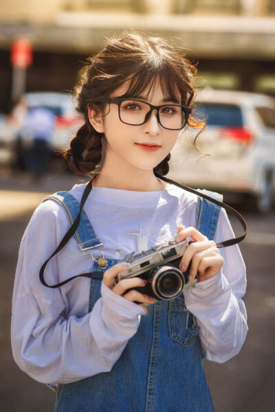 Das Bild eines schönen Mädchens mit langen Haaren, das eine Brille im Frühlingsreise-Fotoset trägt