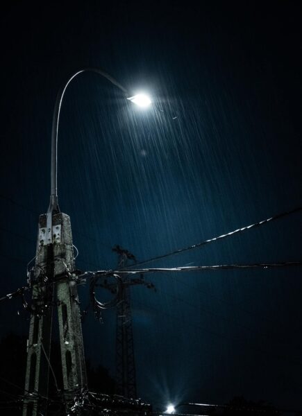 Hình mưa đêm với cây đèn đường và dây điện