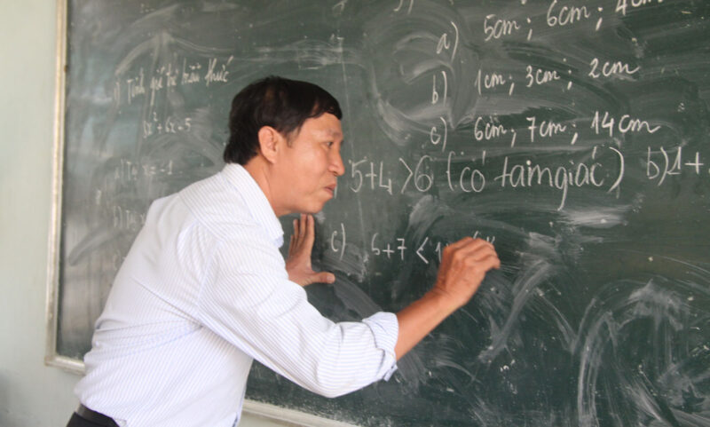 Bild eines Lehrers, der Mathematik an der Tafel löst