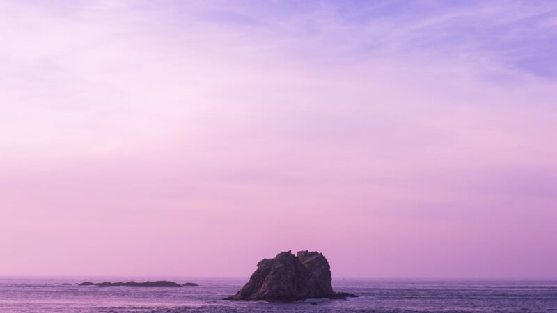 hình nền màu tím có tảng đá nhô lên giữa biển